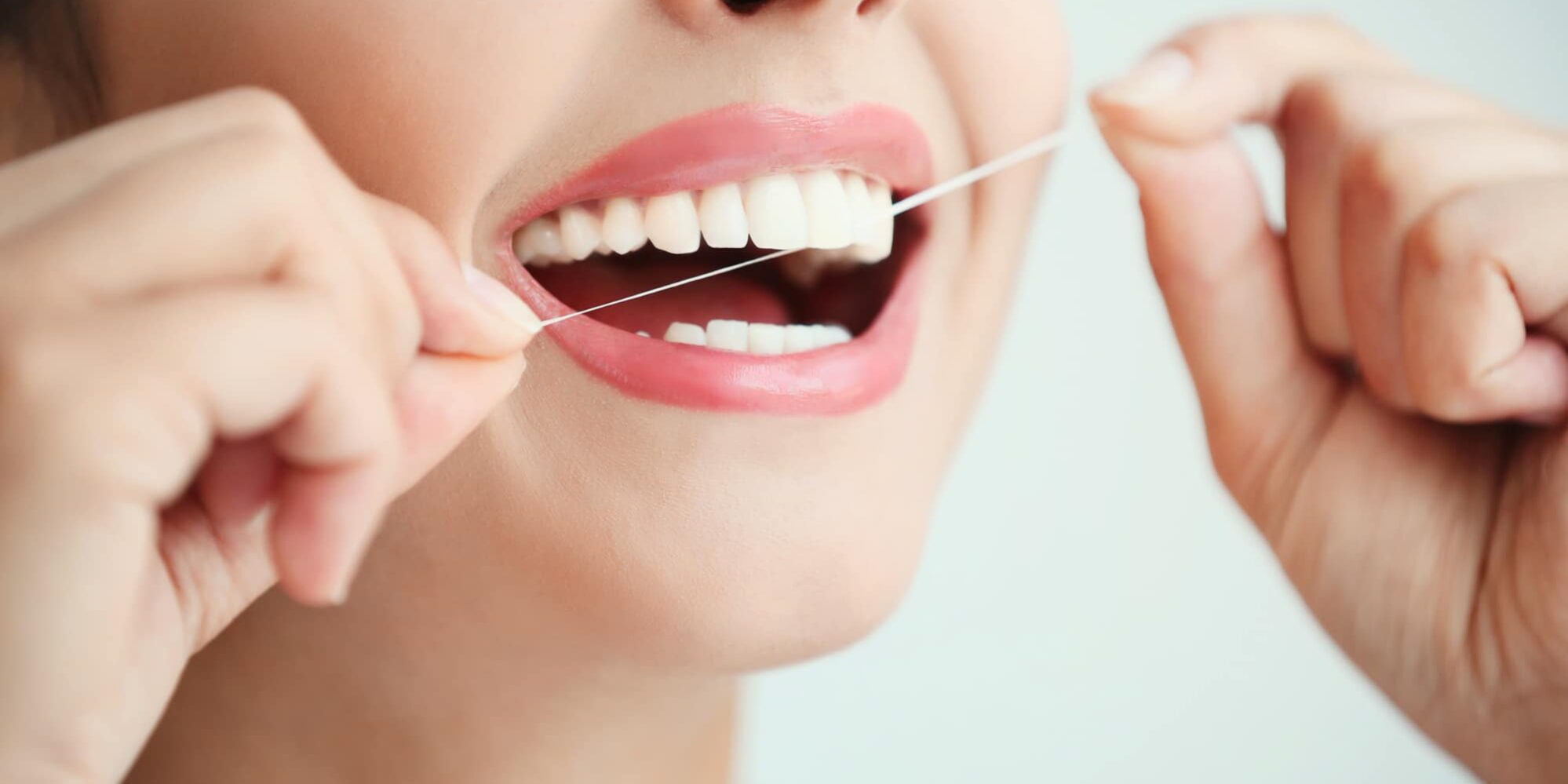 Young woman cleaning teeth with dental floss, close up