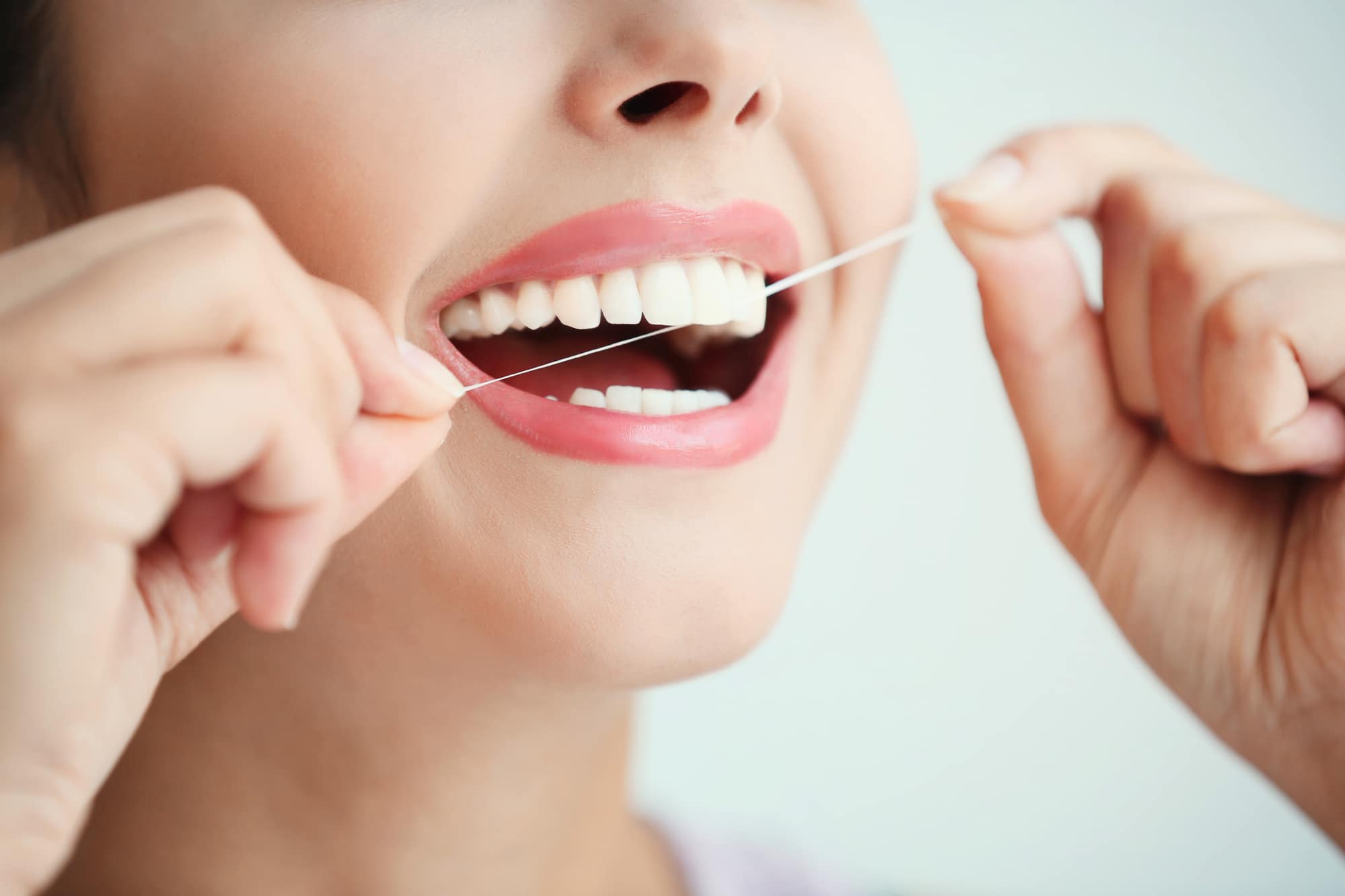 Young woman cleaning teeth with dental floss, close up